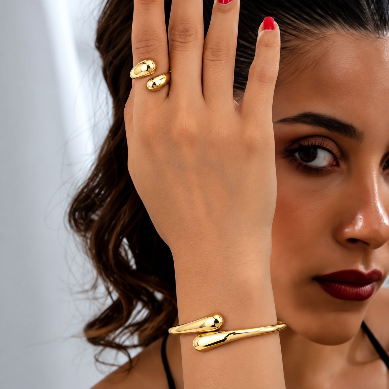 Conjunto de pulsera y anillo dorados de diseño curvo